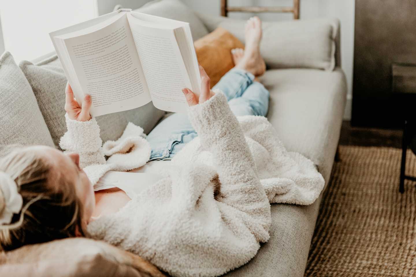 Best copywriting books: Woman lying on sofa reading a book