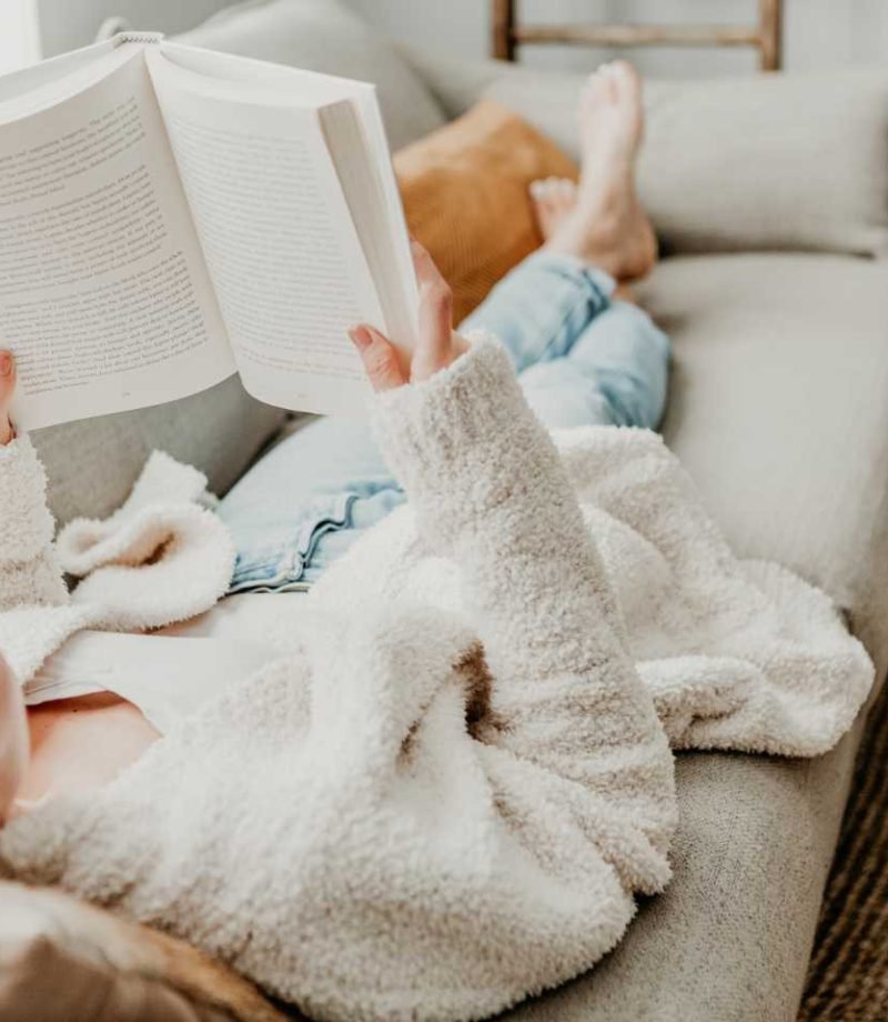 Best copywriting books: Woman lying on sofa reading a book
